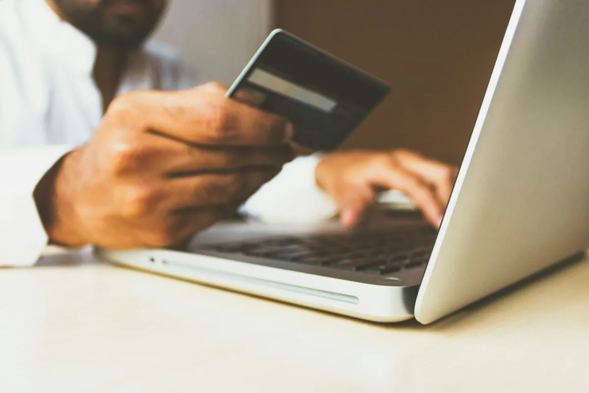 Una persona paga con tarjeta de crédito en una tienda online desde su portátil